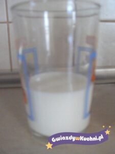 Szklanka mleka na kuchennym blacie, logo Gwiazdy w kuchni na dole.