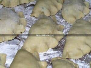 Pierogi z kapustą i grzybami na blacie przed gotowaniem.