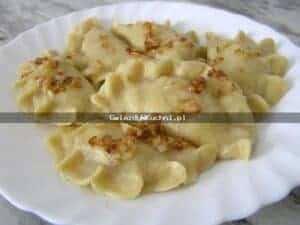 Pierogi z kapustą kiszoną i grzybami na białym talerzu.