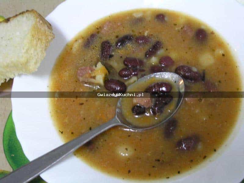 Zupa z fasoli w misce z kawałkiem chleba na boku.