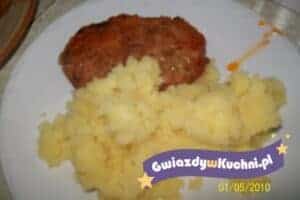 Kotlet mielony z ziemniakami i surówką na talerzu.
