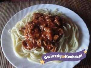 Spaghetti z sosem pomidorowym i mięsem na białym talerzu.
