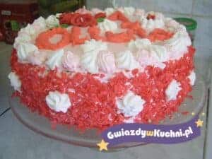 Tort malinowy z dekoracją z bitej śmietany i owoców na talerzu.