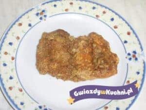 Duszone kotlety wieprzowe na talerzu z dekoracyjnym obrusem.