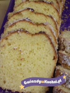 Babka drożdżowa pokrojona na plastry, miękka i puszysta, na tle niebieskiego talerza.