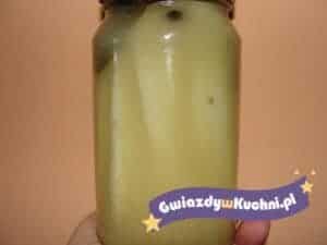 Słoik z ogórkami z musztardą na tle beżowej ściany.