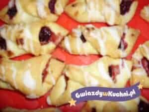 Francuskie rogaliki z dżemem i lukrem na czerwonym tle.