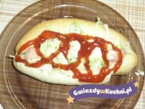 Hot-dog z kiełbasą, sałatą i ketchupem na bułce.