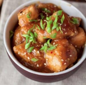 Kurczak słodko-kwaśny w aromatycznym sosie z ananasem, posypany sezamem i szczypiorkiem, idealny na obiad.